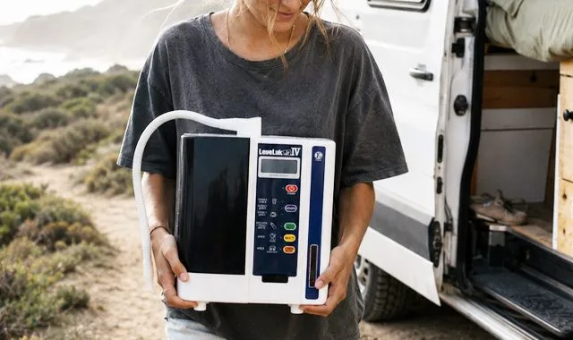 Ein Reisender hält den kompakten LeveLuk JR IV neben einem Wohnmobil an der Küste